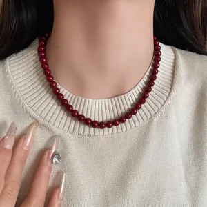 Detailansicht einer Ankora-roten Glasperlenkette auf einem cremefarbenen Strickpullover.