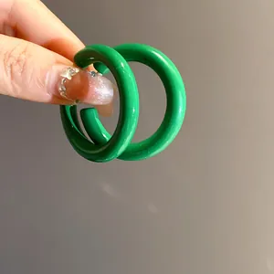 Close-up macro view of vibrant green acrylic C-shaped hoop earrings with glossy finish