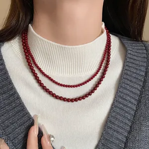 Nahaufnahme einer zweilagigen roten Glasperlenkette im Retro-Stil für elegante Pendleroutfits