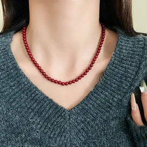 Detailansicht einer Ankara-roten Glasperlenkette an einem Model im grauen Pullover.
