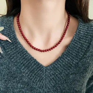 Nahaufnahme einer vintage roten Glasperlenkette auf einem grauen V-Ausschnitt Pullover