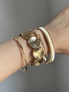 Nahaufnahme von elegantem vergoldetem Armreif-Set mit Hammerschlag-Scheiben für Damen