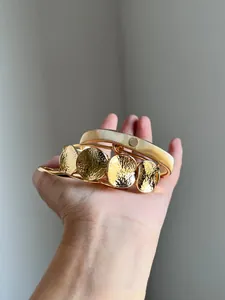 Detailansicht von vier goldfarbenen Metallarmreifen mit verschiedenen Texturen in der Hand