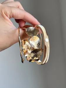 Nahaufnahme eines vierteiligen goldfarbenen Metallarmband-Sets in der Hand gehalten.