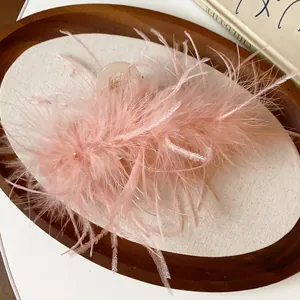 Close-up of elegant pink ostrich feather hair claw clip on minimalist wooden tray