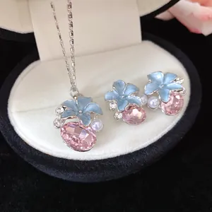 Macro detail of jewelry set with light blue enamel flowers and faceted pink crystals