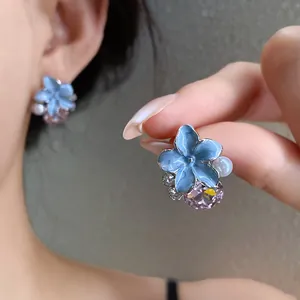 Detailed close-up of a blue enamel flower earring with a pink crystal and pearl