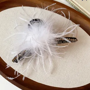 Close-up of fluffy white feathers and rhinestones on a minimalist hair claw clip.