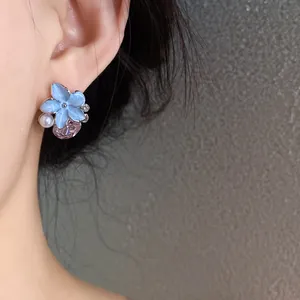 Close-up detail of a French style blue flower earring with pink crystal on a model