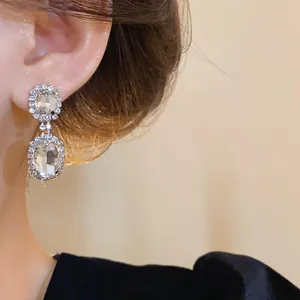 Elegant French style oval crystal drop earrings shown in close-up on a model's ear