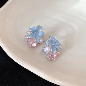 Detail shot of blue flower earrings with pink crystal and pearl accents on a plate