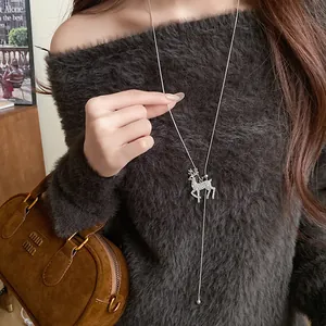 Close-up of a shimmering rhinestone reindeer pendant necklace on a soft grey sweater