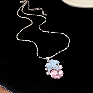 Detailed close-up of a silver necklace pendant featuring a blue flower and pink crystal