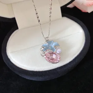 Detailed macro shot of a blue flower and pink crystal pendant necklace in a jewelry box.