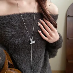 Close-up of elegant rhinestone deer pendant necklace on a grey fuzzy sweater