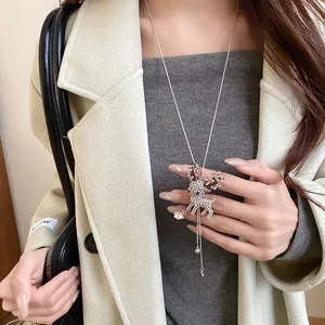 Close-up of sparkling rhinestone deer pendant necklace worn with an elegant cream coat