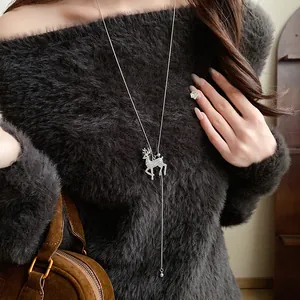 Detailed shot of sparkling reindeer necklace on model with grey fuzzy sweater