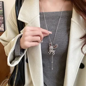Close-up of a sparkling rhinestone deer pendant necklace on a model's outfit.