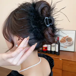 Detail view of an elegant black feather hair claw clip used for a sophisticated bun hairstyle.