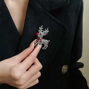Detailed view of a sparkling rhinestone reindeer brooch with red accents on a coat