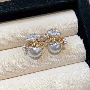 Detailed macro view of elegant gold-plated stud earrings with firework zircons and pearls.