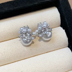 Close-up view of elegant pearl stud earrings featuring a shimmering fireworks zircon cluster