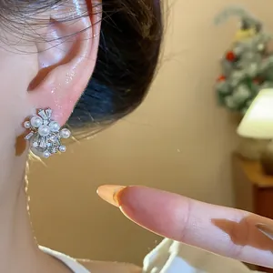 Detailed view of elegant firework-style pearl and cubic zircon stud earrings on ear