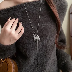Detailed close-up of a long silver-tone necklace with a sparkling rhinestone reindeer pendant.