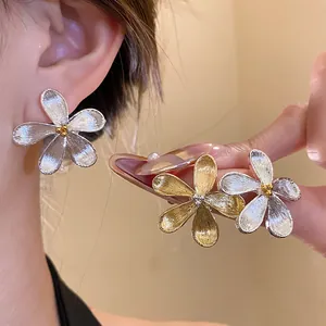Close-up of elegant flower stud earrings with brushed metallic texture