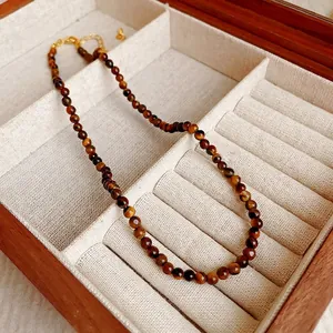 Collier vintage en perles d'oeil de tigre avec fermoir doré dans un écrin en bois.