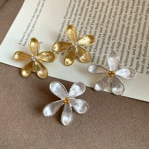 Macro detail of elegant gold and silver textured flower stud earrings with bead centers.