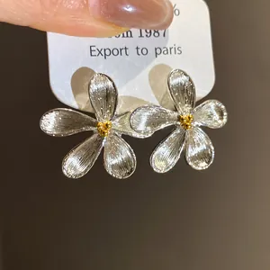 Close-up macro detail of silver flower stud earrings featuring textured metal petals