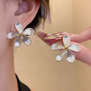 Detailed close-up of silver textured flower stud earrings with gold stamen accents