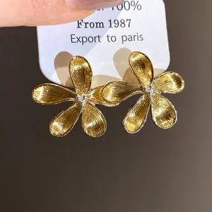 Detailed macro view of elegant gold brushed flower stud earrings with silver centers
