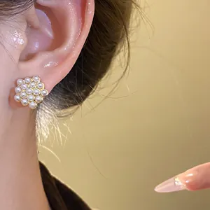 Close-up detail showing the elegant pearl cluster stud earring worn on a female model's ear