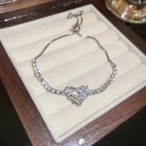 Detail shot of a sparkling heart-shaped zircon bracelet displayed in a wooden jewelry box.