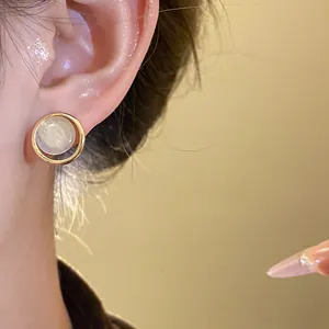 Close-up of elegant gold geometric stud earring with shimmering cat-eye stone
