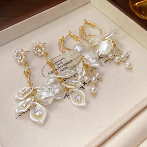 Close-up detail of elegant white pearl flower petal tassel earrings in a wooden jewelry box