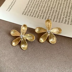 Detailed macro view of golden five-petal flower stud earrings with pearl centers