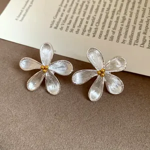 Detailed macro view of elegant silver flower stud earrings with gold center beads