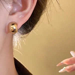 Detailed close-up showing a minimalist polished gold chunky hoop earring worn on an earlobe