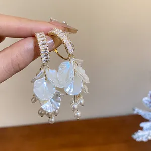 Close-up of elegant vintage drop earrings with zircons, petals, and pearl tassels