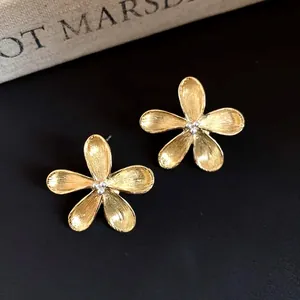 Detailed view of elegant gold-toned five-petal flower stud earrings with silver beads.