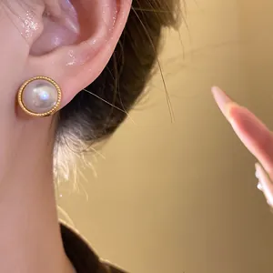 Close-up view of an elegant vintage gold-rimmed pearl earring shown worn on a model's ear