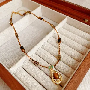 Vue détaillée du collier vintage en perles d'œil de tigre avec pendentif goutte d'or