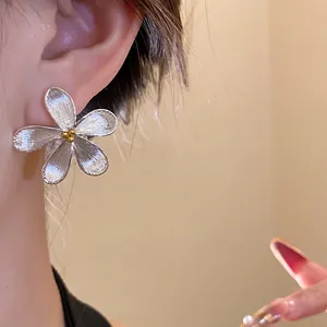 Detailed view of silver flower stud earrings with an elegant brushed metal texture finish.