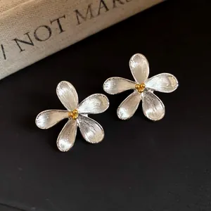 Detailed view of elegant silver flower stud earrings with a golden textured center