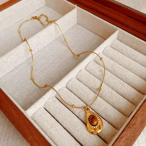Gros plan d'un collier doré avec pendentif ovale en œil de tigre dans un coffret