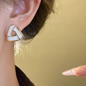 Close-up shot of a geometric triangle earring featuring white enamel and gold metal trim