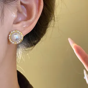 Close-up view of an elegant gold stud earring with a large pearl and small pearl trim.